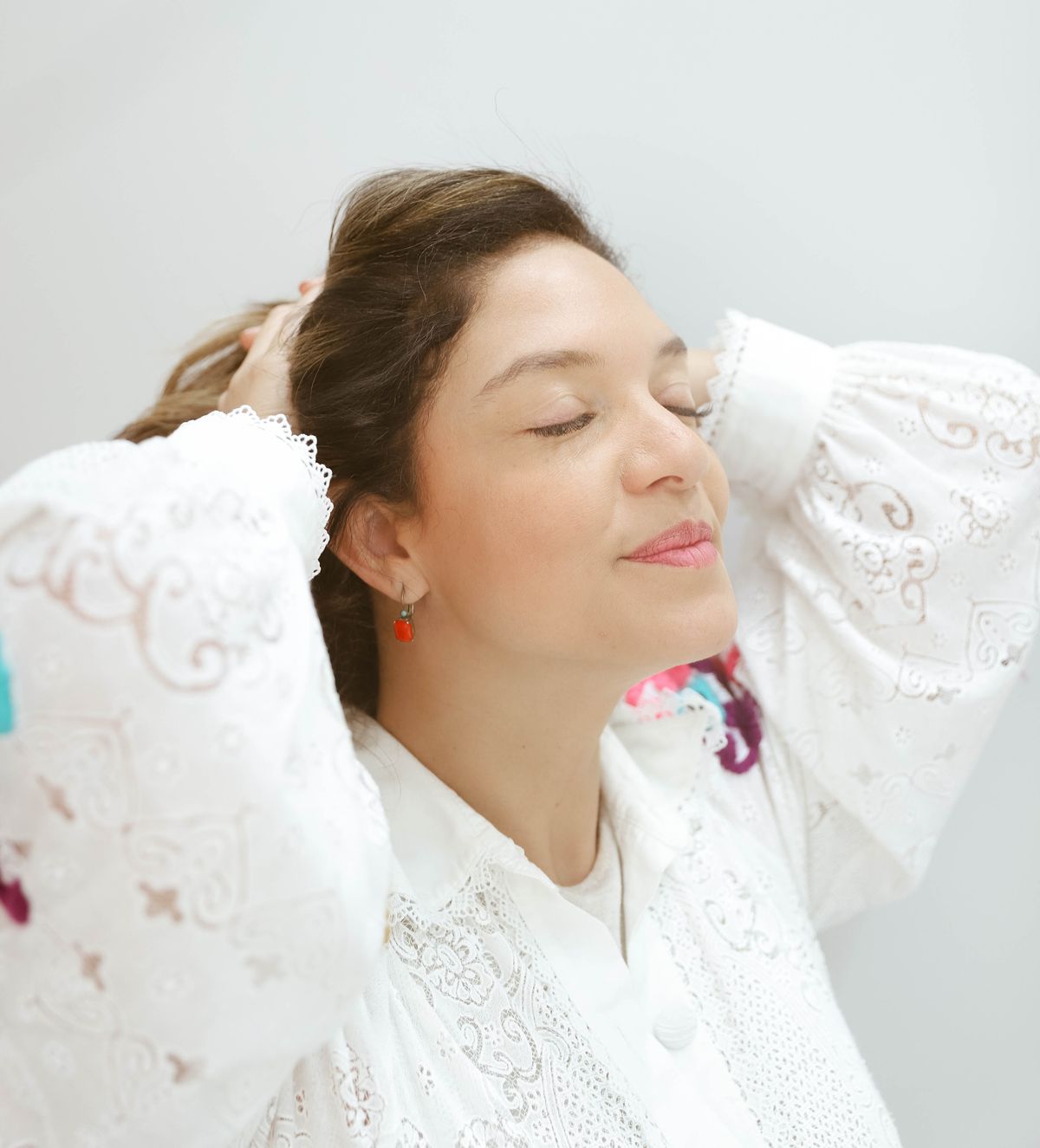 Dra. Rowena Moraes de olhos fechados, sorrindo, com as mãos nos cabelos