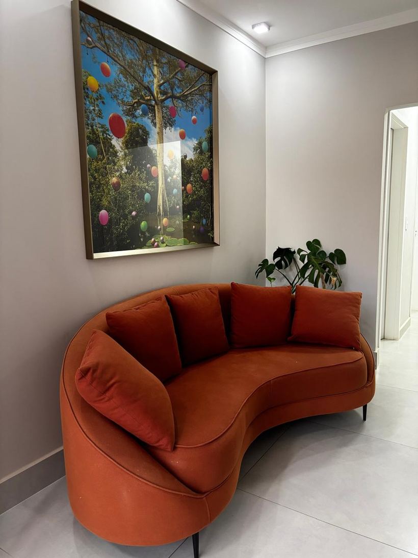 Sala de espera com sofá laranja curvo e quadro